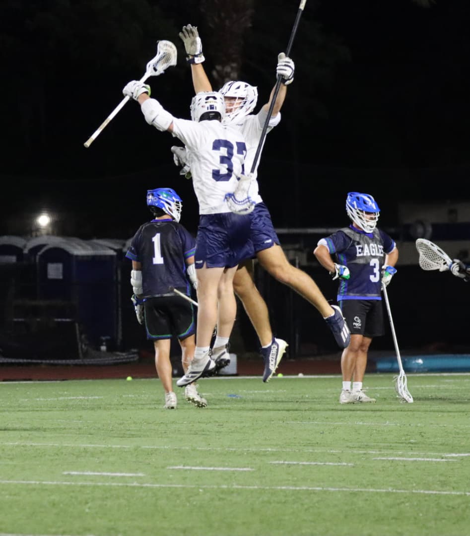Two GS players leaping to celebrate a goal under the lights